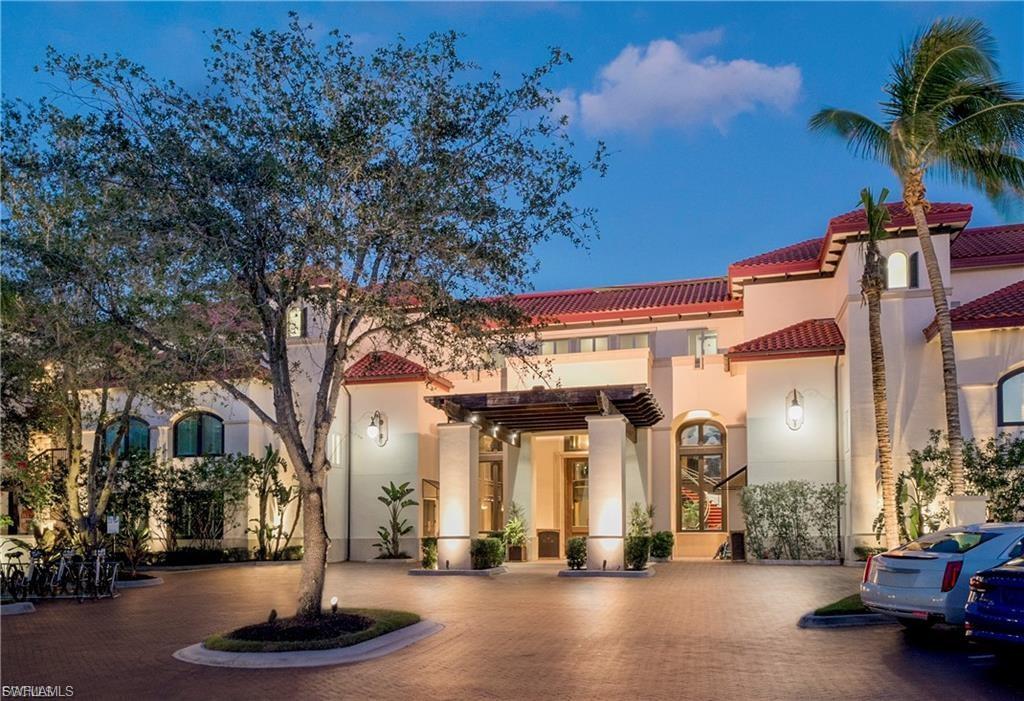 Mediterranean-style exterior featuring a terracotta tile roof, stucco facade, arched windows, decorative wall sconces, and a covered entry with columns