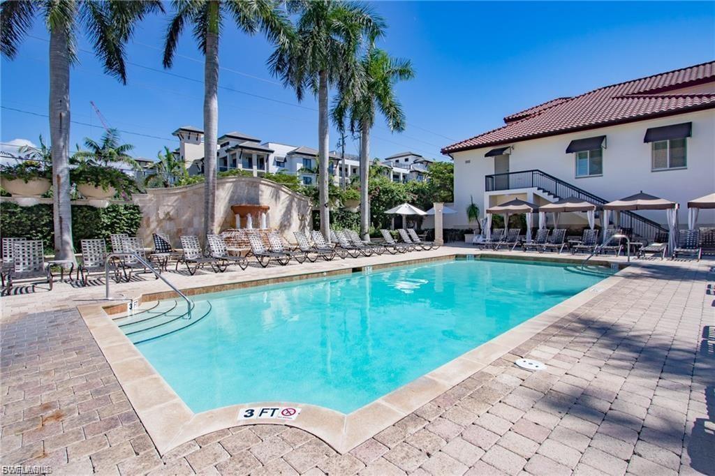Expansive outdoor pool area featuring a rectangular pool with integrated steps, surrounded by paver decking