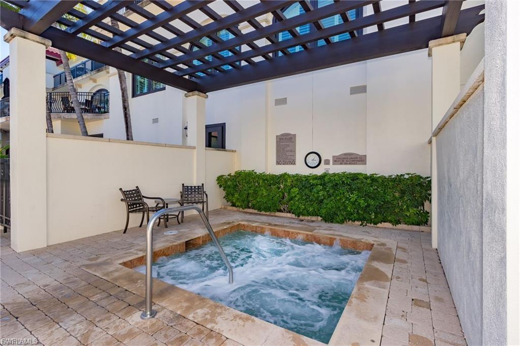 Outdoor spa with integrated steps and a stainless steel grab rail, surrounded by light-toned pavers