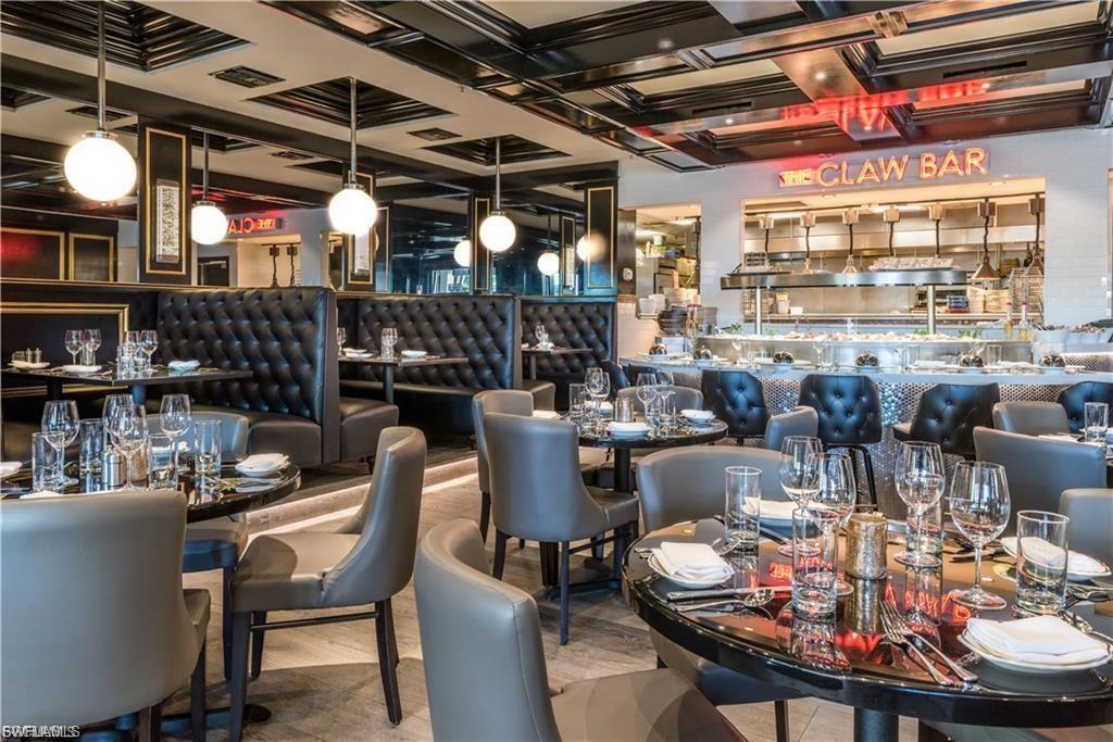 Refined dining area featuring booth seating with tufted upholstery, round tables with a glossy finish, and sleek pendant lighting