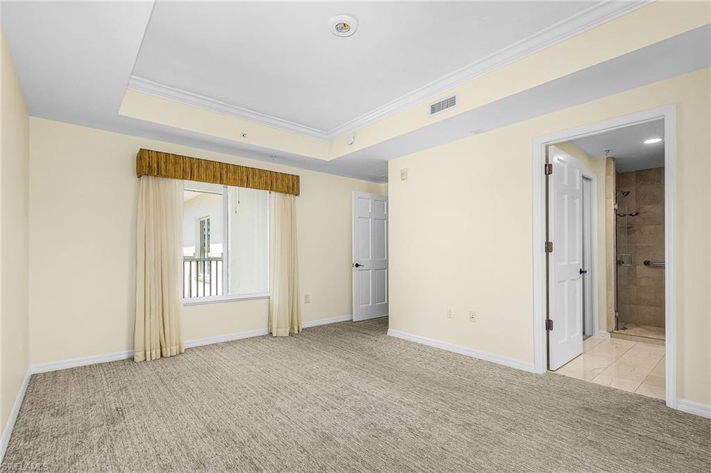 Spacious room featuring tray ceilings with crown molding, recessed lighting, and neutral carpeting