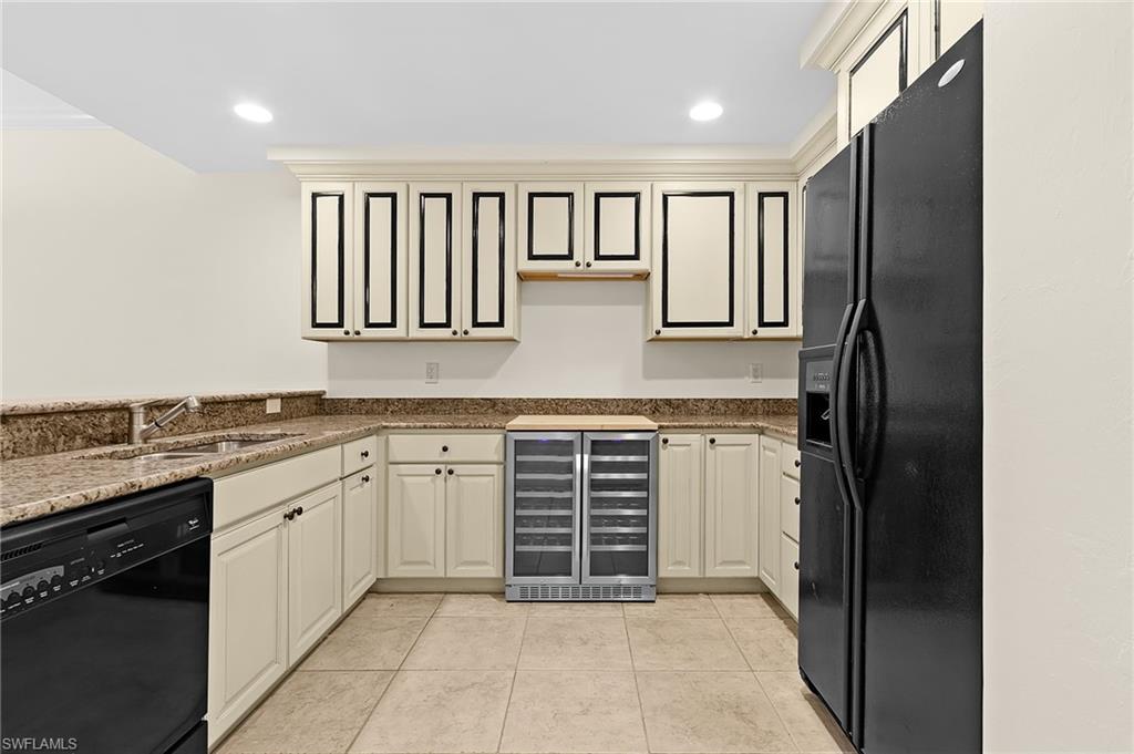 U-shaped kitchen area featuring cream cabinetry with black trim details, granite countertops, and tile flooring
