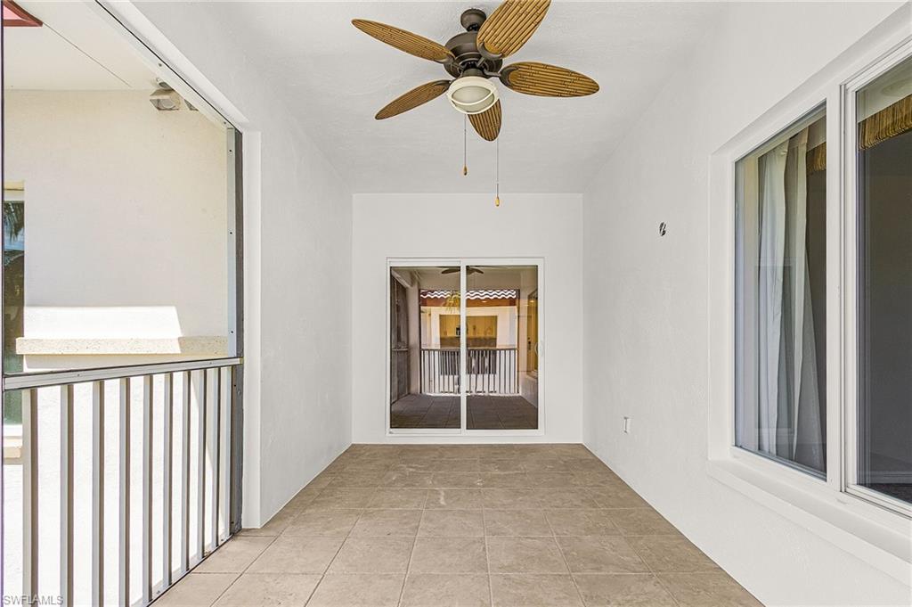 Screened outdoor living area featuring tile flooring, a ceiling fan with integrated lighting, and white walls