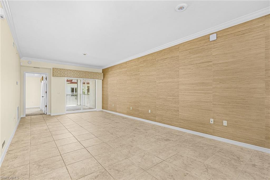 Spacious room featuring tile flooring, a textured accent wall, crown molding, and recessed lighting