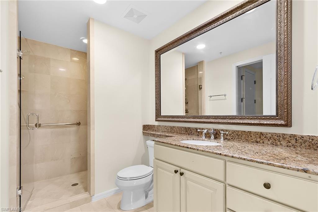 Bathroom featuring a walk-in shower with glass enclosure, beige tiled walls, and a grab bar