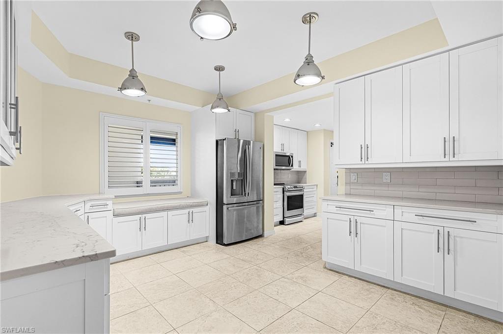 Kitchen featuring white shaker-style cabinetry, light-toned countertops, and stainless steel appliances