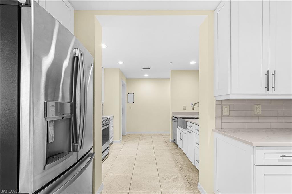 Modern kitchen featuring stainless steel appliances, white shaker cabinetry, light-toned countertops, subway tile backsplash, and recessed lighting