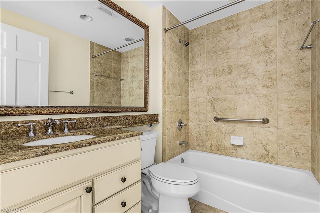 Bathroom with a single vanity featuring a stone countertop, an undermount sink, and a framed mirror