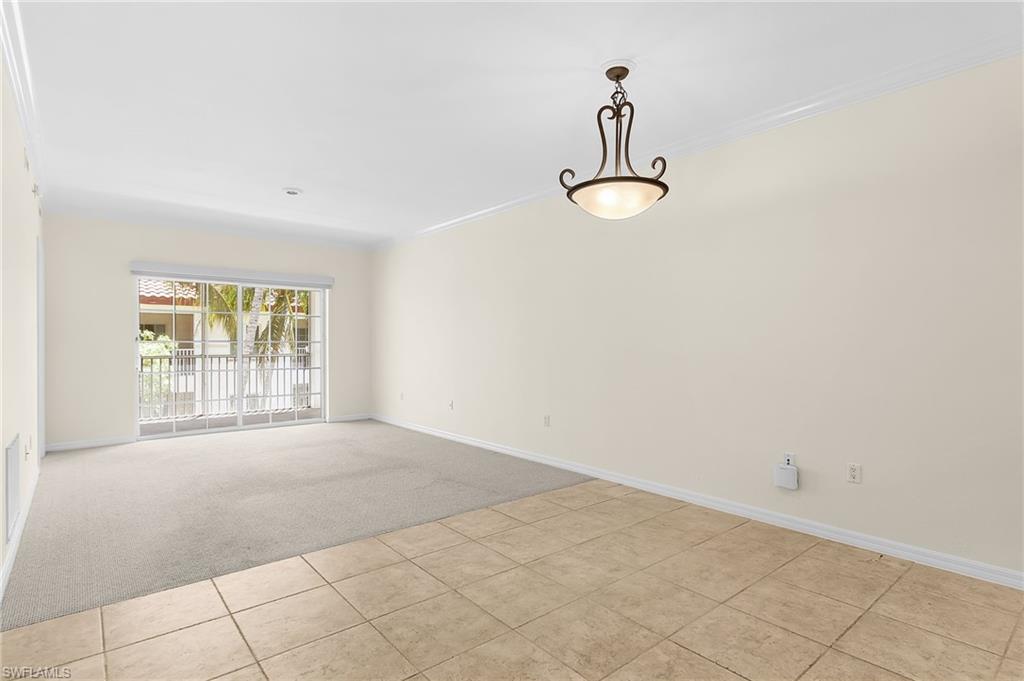 Spacious interior featuring a combination of neutral-toned carpeting and tile flooring, crown molding, and a decorative ceiling fixture