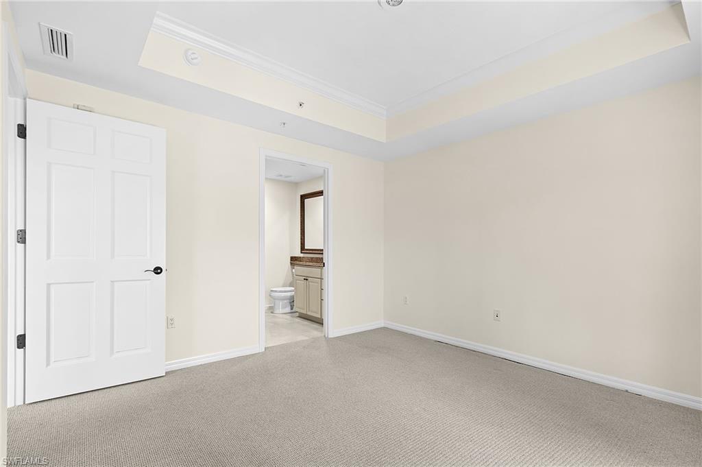 Spacious room with plush carpet flooring, light-toned walls, and a tray ceiling with crown molding