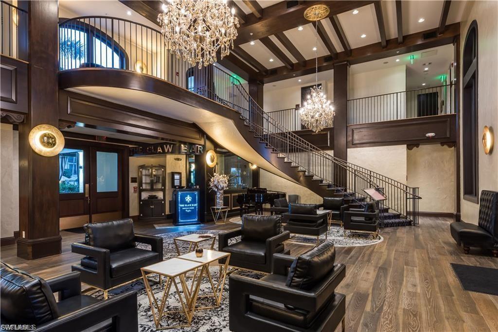 Grand foyer featuring a coffered ceiling with exposed wood beams, a curving staircase with wrought iron railing, and wood-finish flooring