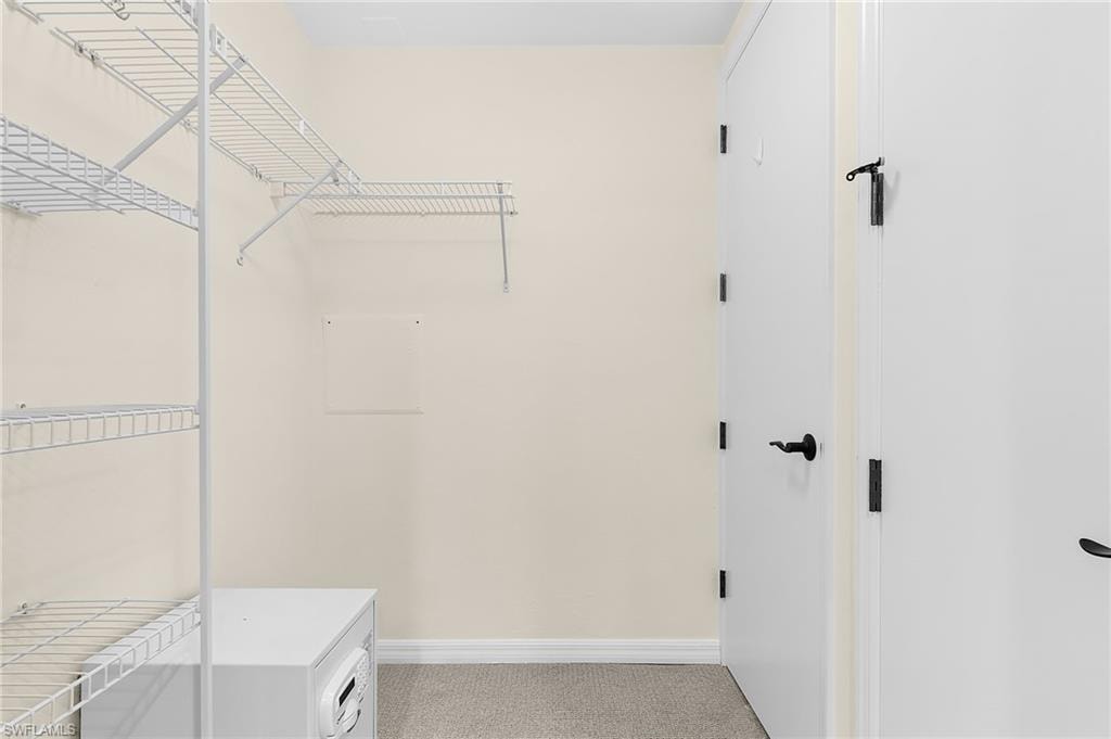 Walk-in closet featuring wire shelving, wire hanging rods, neutral wall paint, white baseboards, and carpet flooring