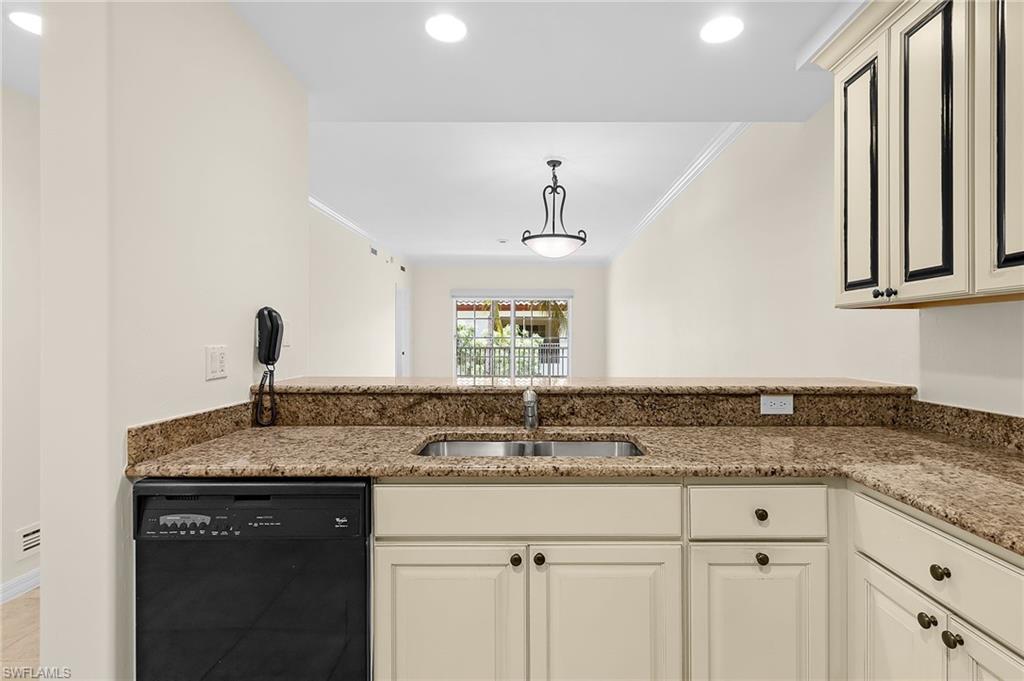 Kitchen with granite countertops, stainless steel sink, black dishwasher, and cream cabinetry with dark hardware