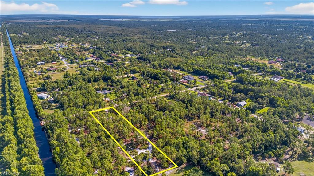Aerial view of property and surrounding area featuring property boundaries highlighted and a forest