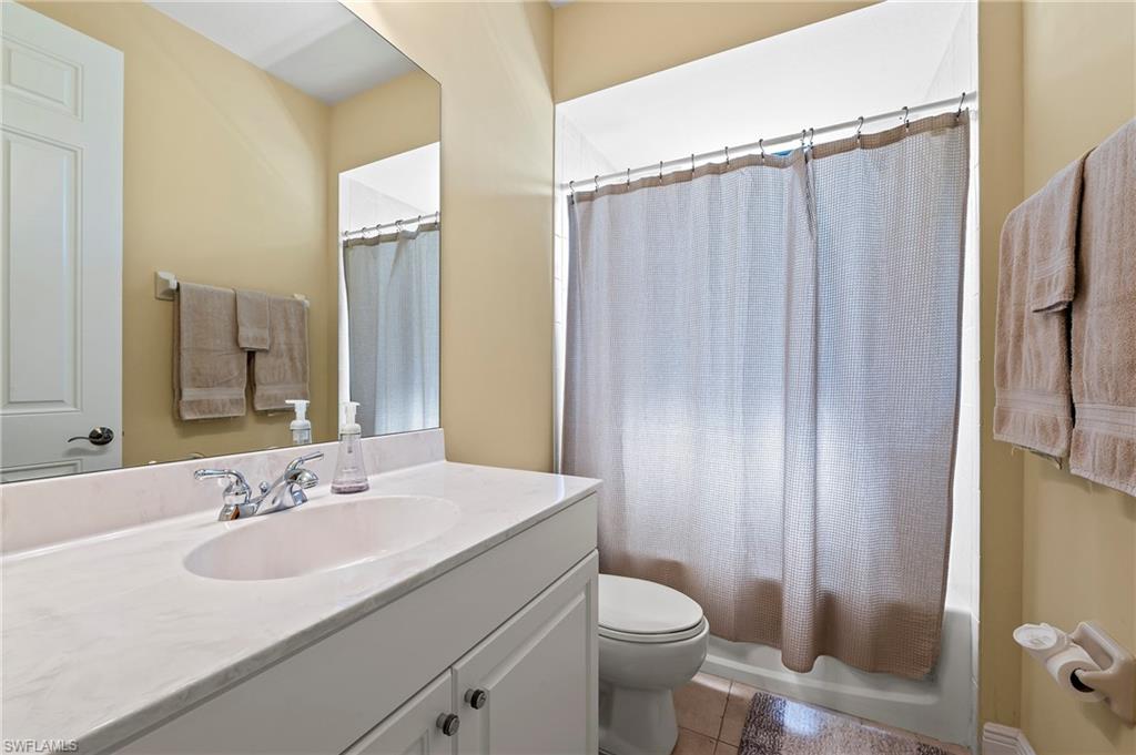 Full bath with toilet, tile patterned floors, vanity, and shower / bath combo with shower curtain