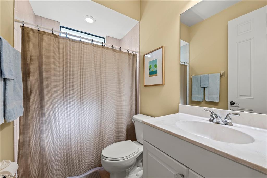 Bathroom featuring toilet, vanity, and a shower with curtain