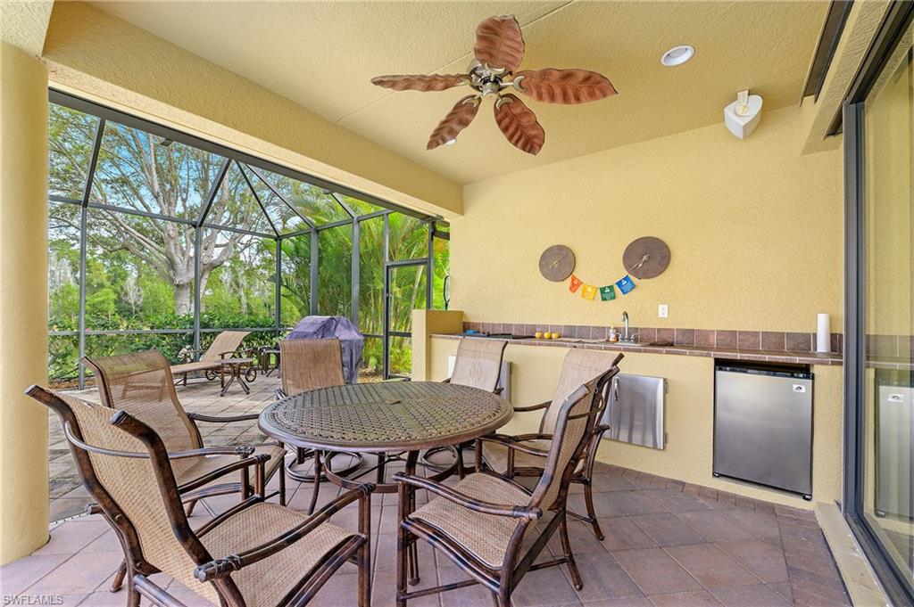View of patio / terrace with an outdoor kitchen, a lanai, a ceiling fan, a sink, and outdoor dining area
