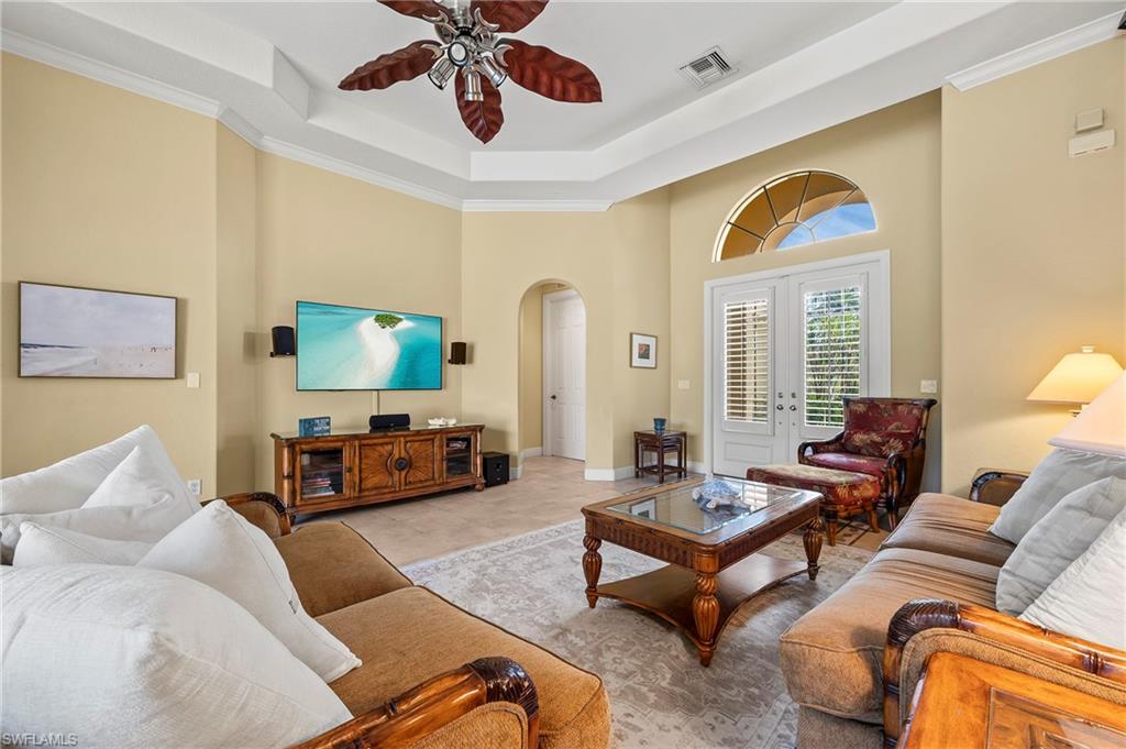 Living room with arched walkways, ceiling fan, a high ceiling, french doors, and a tray ceiling