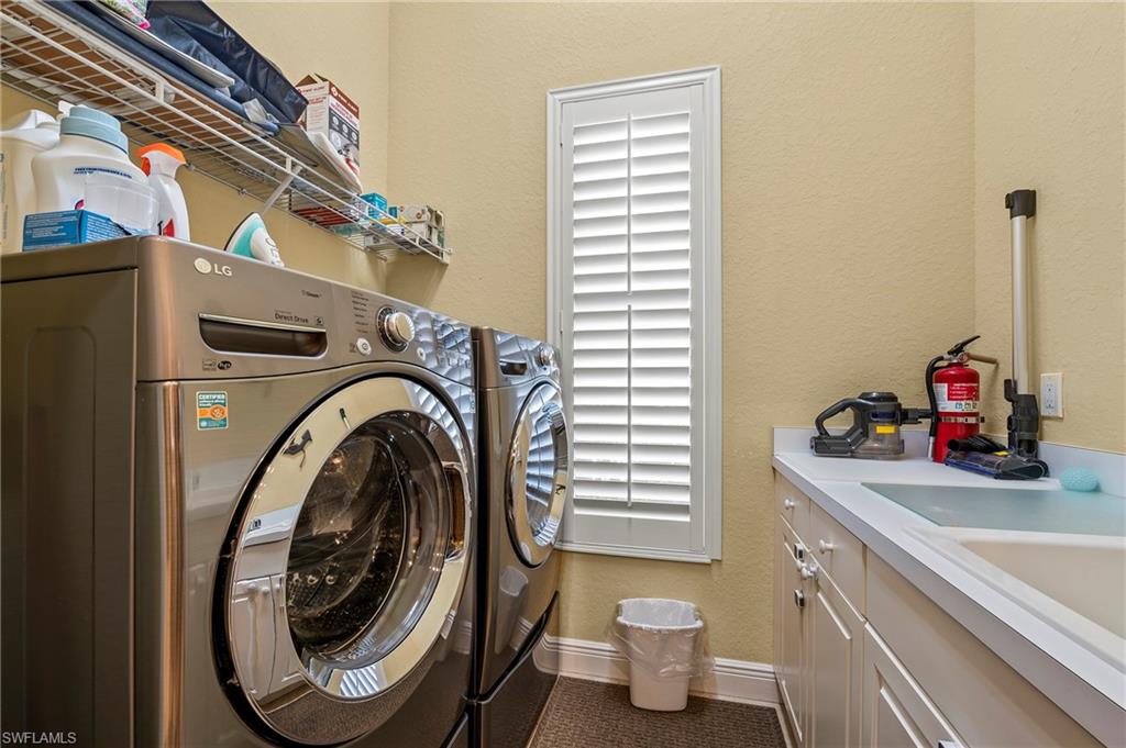 Laundry area with separate washer and dryer, cabinet space, and tile patterned floors