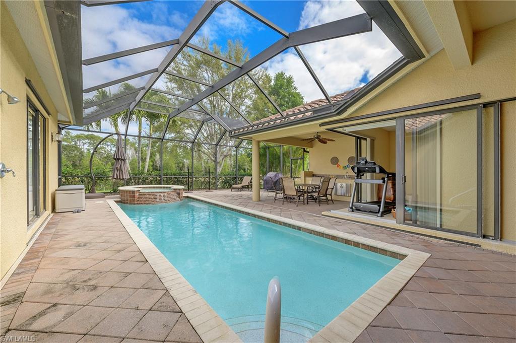 View of pool with a patio area, a pool with connected hot tub, glass enclosure, outdoor dining space, and ceiling fan