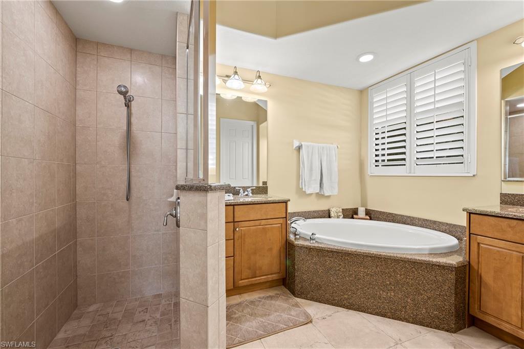 Bathroom with a tile shower, a garden tub, two vanities, and recessed lighting