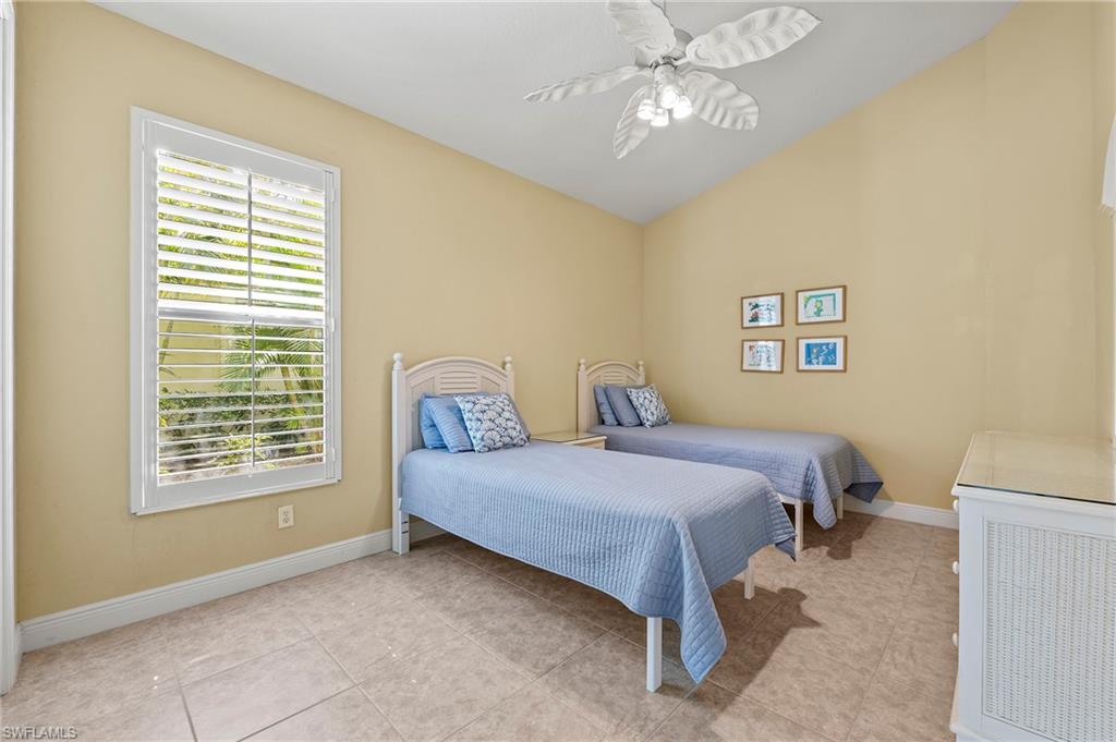 Bedroom with light tile patterned flooring, baseboards, a ceiling fan, and vaulted ceiling