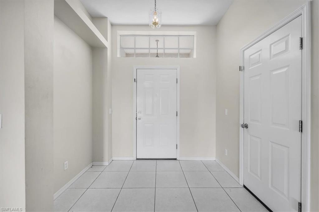 Entryway featuring a panel door with transom window, tile flooring, recessed architectural detailing, and a pendant light fixture