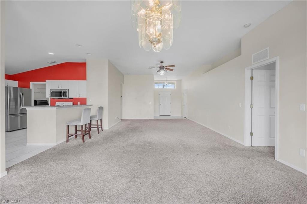 Open-concept living area featuring vaulted ceilings, recessed lighting, and a prominent decorative chandelier