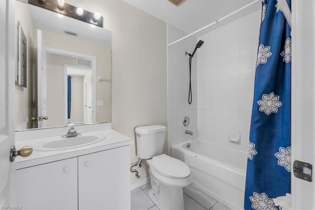Bathroom featuring a single vanity with an integrated sink, white cabinetry, a rectangular mirror, and an overhead light fixture