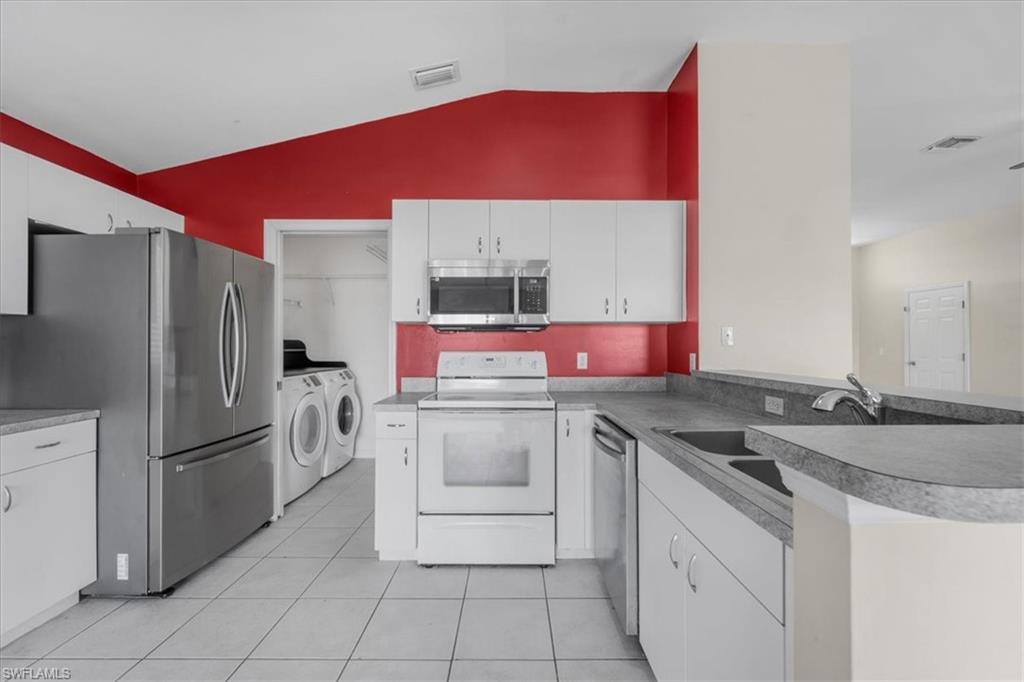 Kitchen featuring white cabinetry, stainless steel refrigerator, white range, built-in microwave, and light-toned countertops