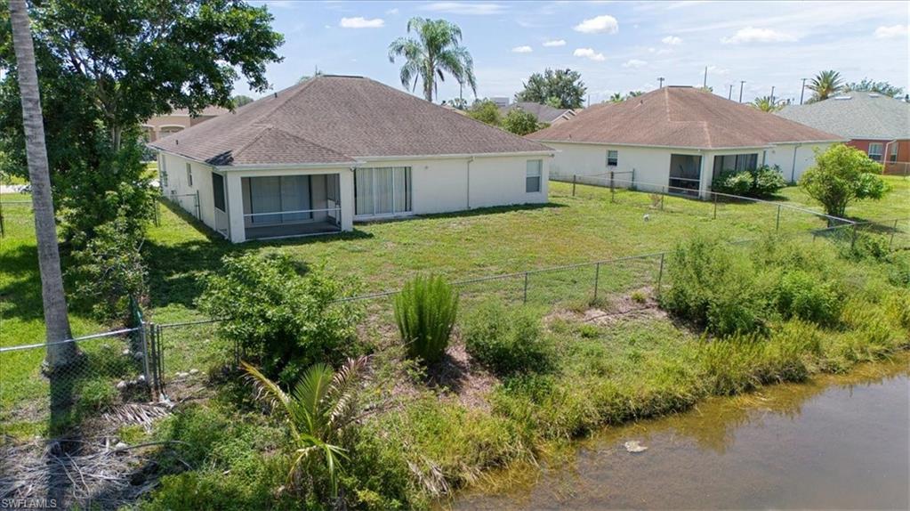 Rear exterior featuring a screened patio and verdant landscaping