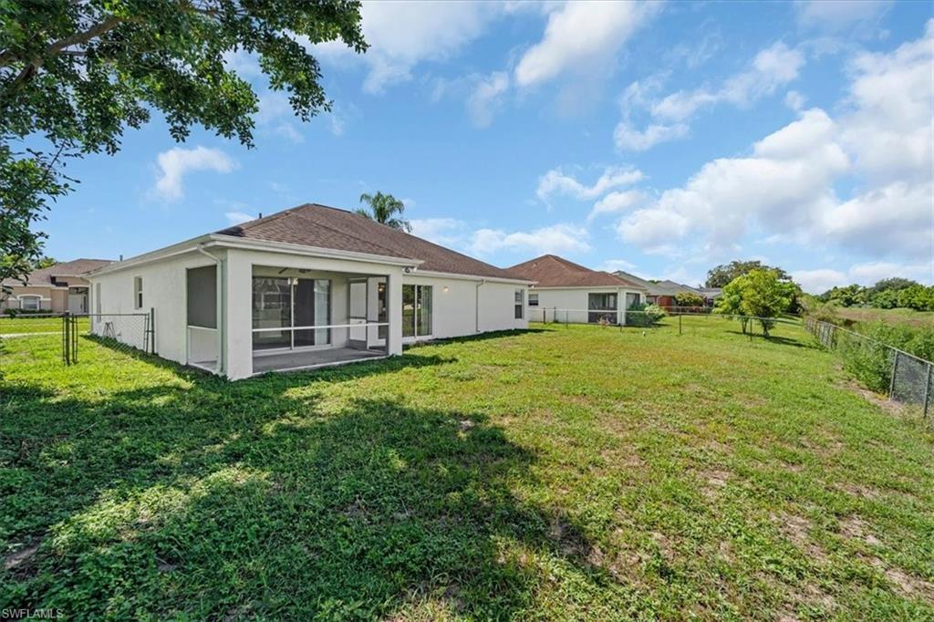 Expansive backyard featuring a screened-in patio, mature trees, and a chain-link fence