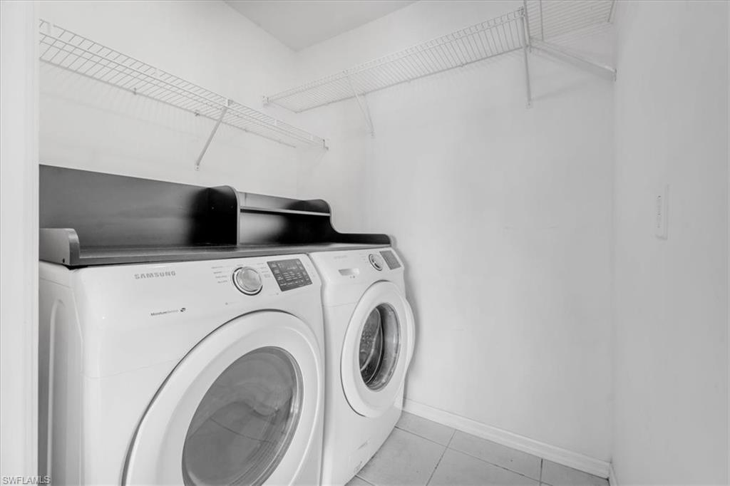 Dedicated laundry area featuring front-loading appliances, overhead wire shelving, and tiled flooring
