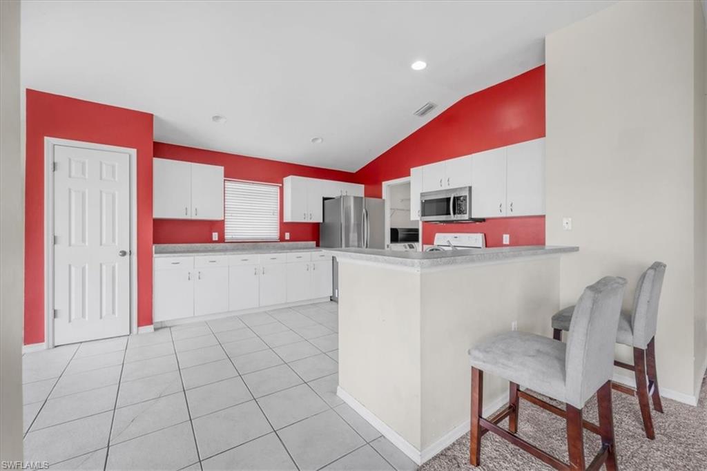 Kitchen featuring white cabinetry, stainless steel appliances, a breakfast bar, and tile flooring