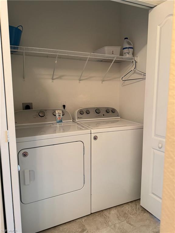 Dedicated laundry closet featuring a washer and dryer, wire shelving, and neutral tone flooring