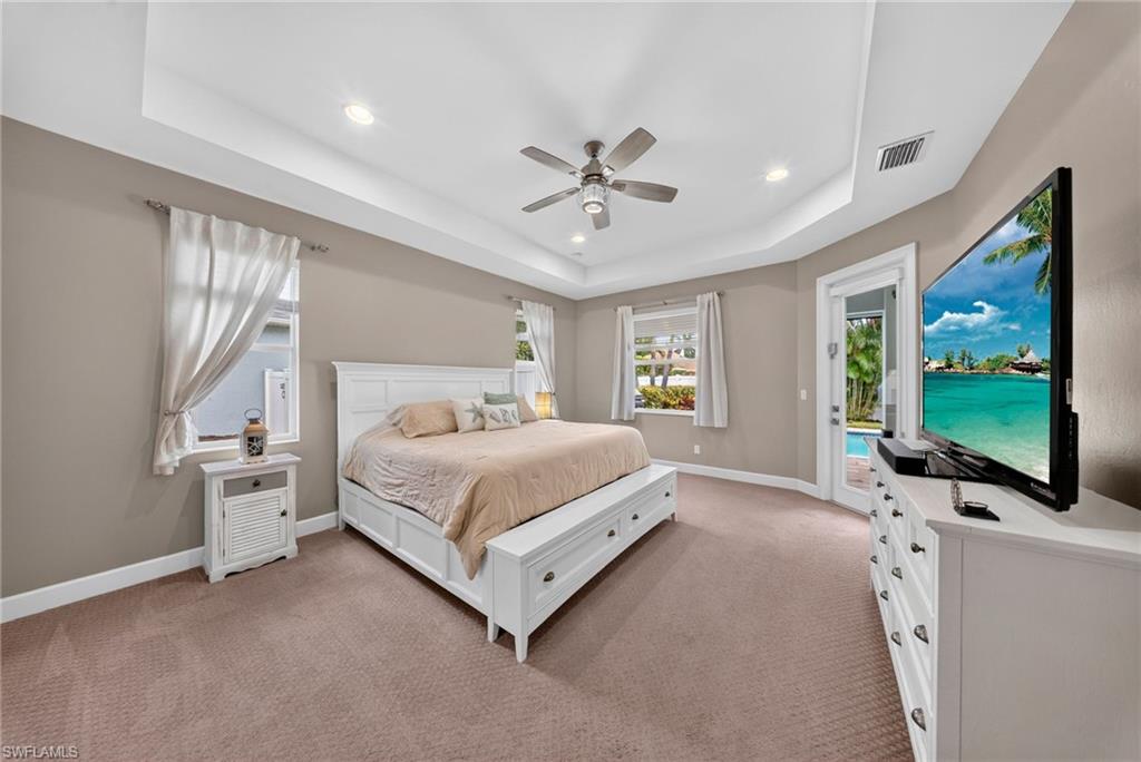 Expansive room featuring a tray ceiling with recessed lighting and a ceiling fan