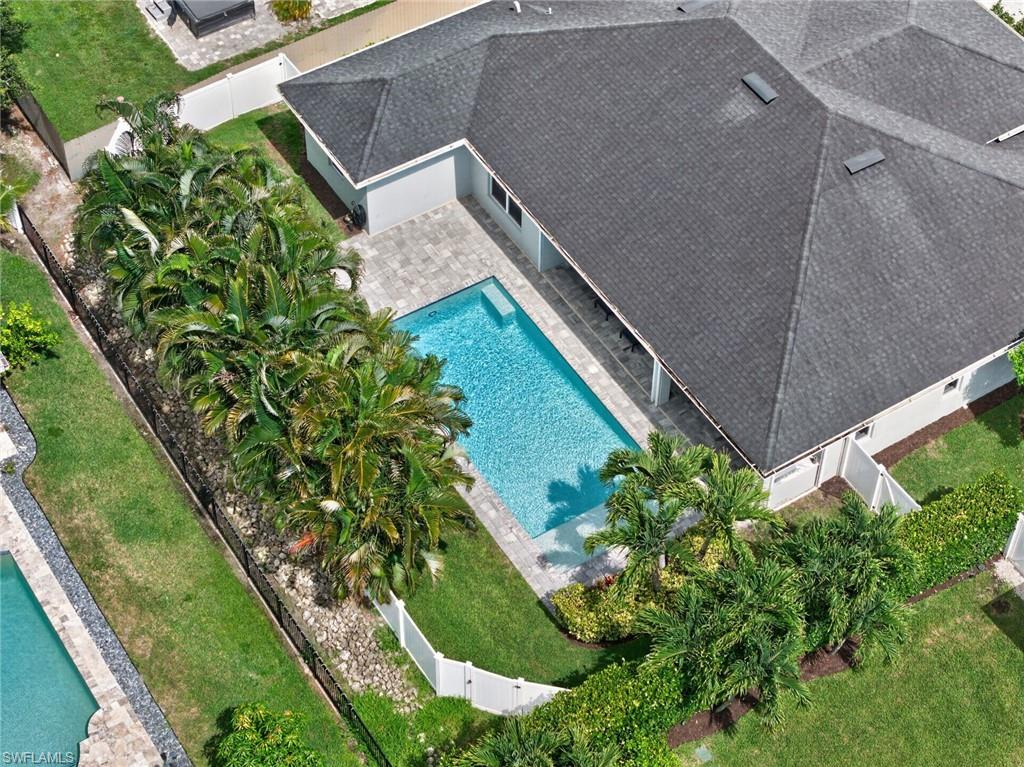 Backyard oasis featuring a rectangular swimming pool, surrounding paver patio, and lush landscaping