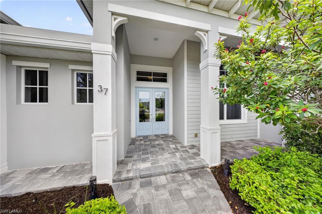 Welcoming entryway featuring light blue double doors, grey paver walkway, and white architectural columns