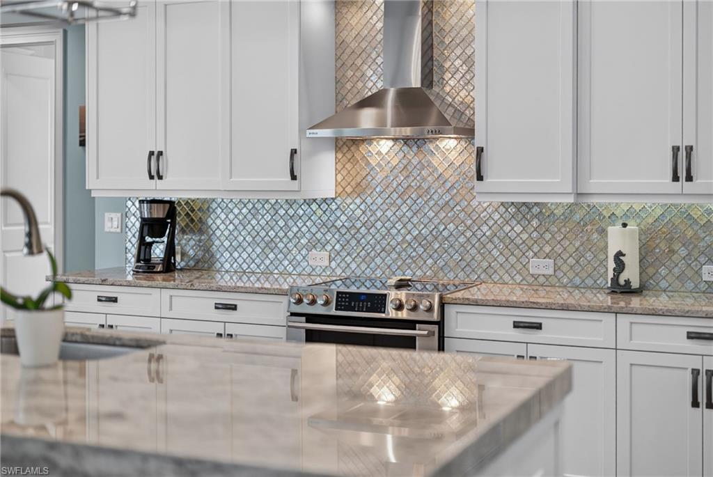 Contemporary kitchen featuring white shaker cabinetry with dark hardware, a stainless steel range hood, and a built-in electric range