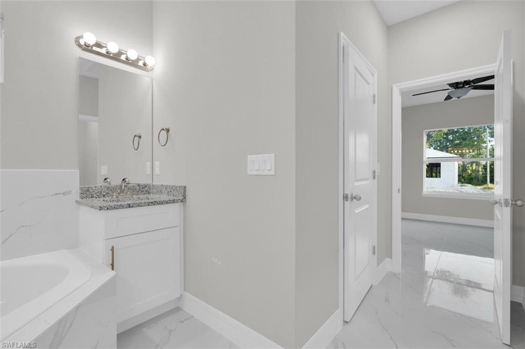 Bathroom vanity with a granite countertop, undermount sink, and brushed nickel faucet