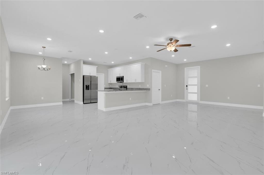 Open-concept living space featuring expansive light-toned tile flooring, recessed ceiling lighting, and a kitchen with white cabinetry