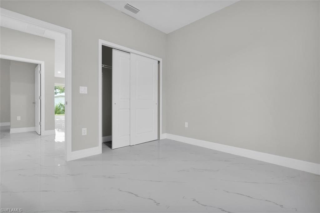 Spacious room featuring light gray walls, white baseboards, and marble-look tile flooring