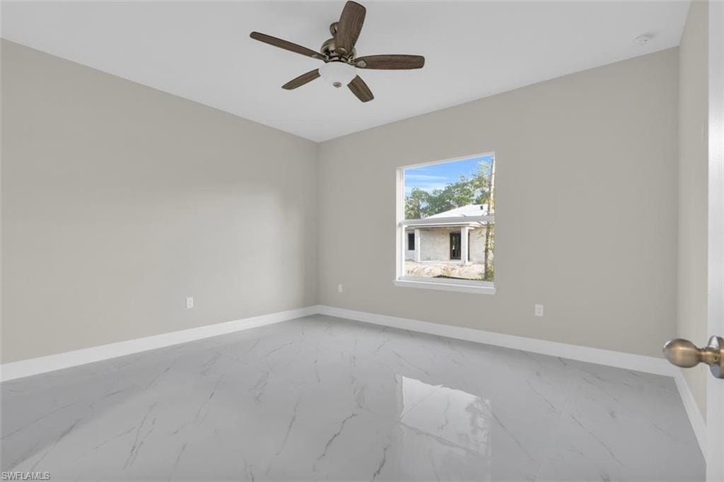 Bright room featuring light gray walls, white baseboards, and large format marble-look tile flooring