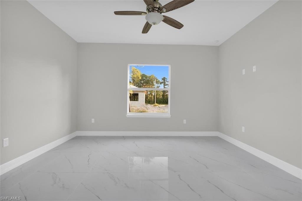 Spacious room featuring light gray walls, white baseboards, and large format tile flooring