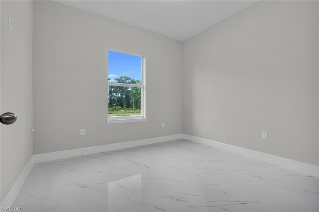 Bright room featuring a single window, light gray walls, white baseboards, and white tile flooring with gray veining