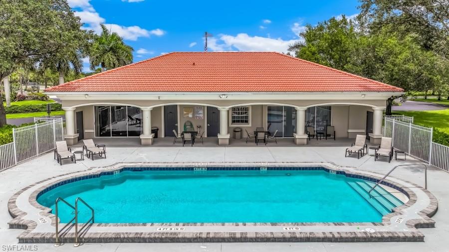Oval-shaped swimming pool with integrated steps, surrounded by a concrete deck with a low privacy fence