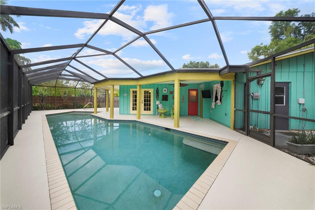 Screened-in swimming pool featuring a light-colored deck surround, integrated steps, and handrails