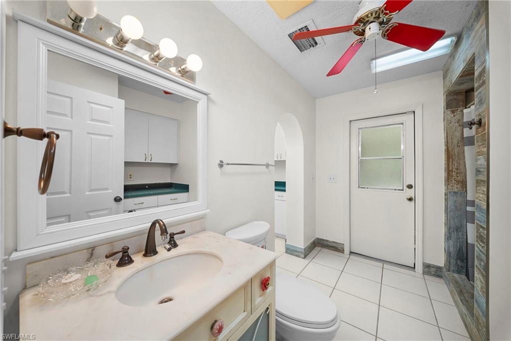 Bathroom featuring a single vanity with a solid surface countertop, an undermount sink, and a bronze-finish faucet