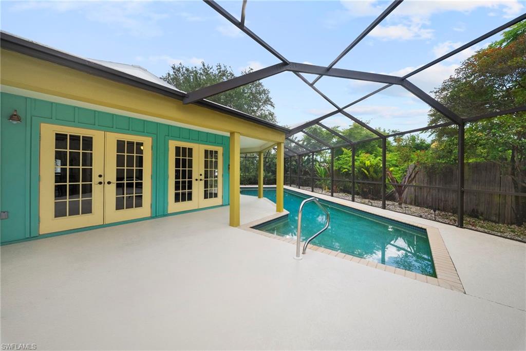 Enclosed swimming pool with a screen enclosure, ample patio decking, and direct access through multiple sets of French doors