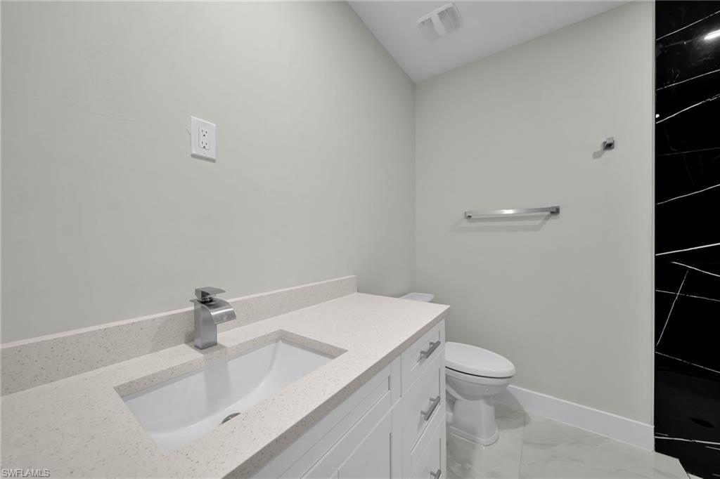 Bathroom vanity featuring a light speckled countertop, undermount sink, and contemporary chrome faucet